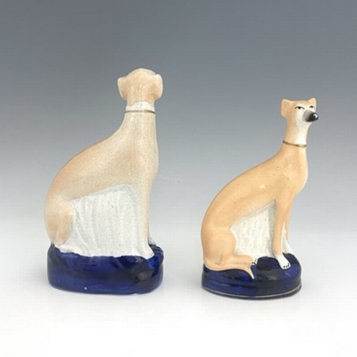 1024 - Two Staffordshire pearlware greyhounds, circa 1840, painted in light brown enamel, seated on cobalt ... 