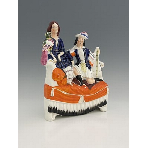 1026 - A Staffordshire figure of a seated man and woman on a chaise, circa 1870, female figure is modelled ... 