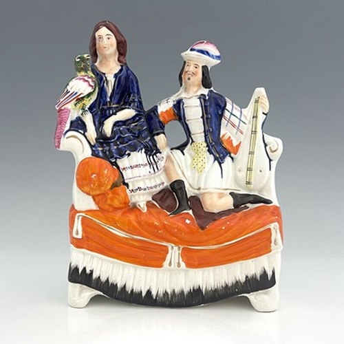 1026 - A Staffordshire figure of a seated man and woman on a chaise, circa 1870, female figure is modelled ... 