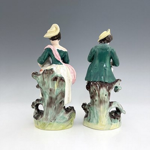 1031 - A pair of Staffordshire pastoral figures, circa 1870, standing female figure modelled with a brown a... 