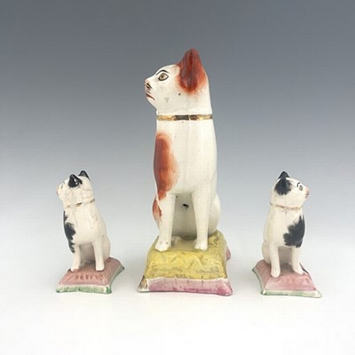 1036 - Three Staffordshire pottery cats, 19th century, including a pair of black and white cats on pink cus... 