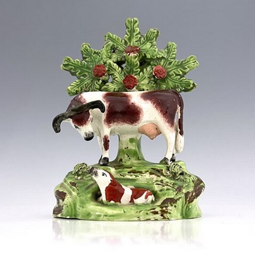 1042 - A Staffordshire boccage figure of a cow and calf, circa 1820, modelled in relief with applied rosett... 