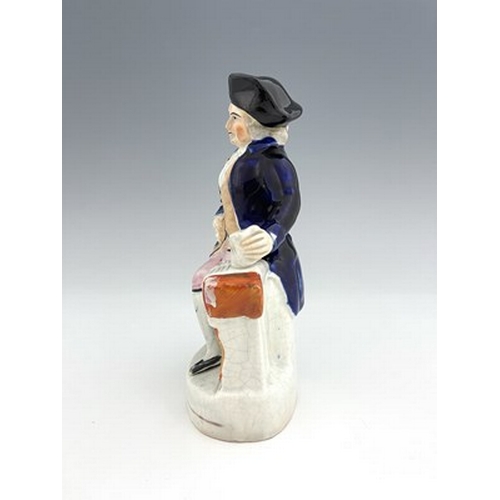 1050 - A Staffordshire figure, circa 1850, modelled seated in cobalt blue coat and tricorn hat, his left ha... 