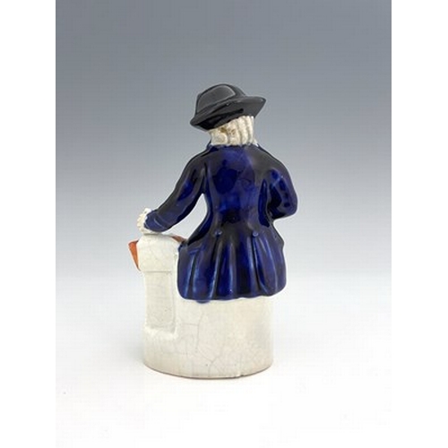 1050 - A Staffordshire figure, circa 1850, modelled seated in cobalt blue coat and tricorn hat, his left ha... 