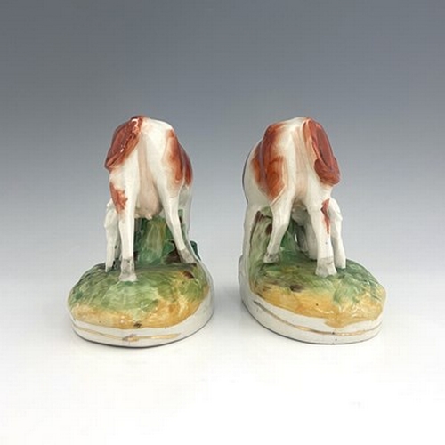 1059 - A pair of Staffordshire cows with calves, modelled standing beside a running stream with gilt line t... 