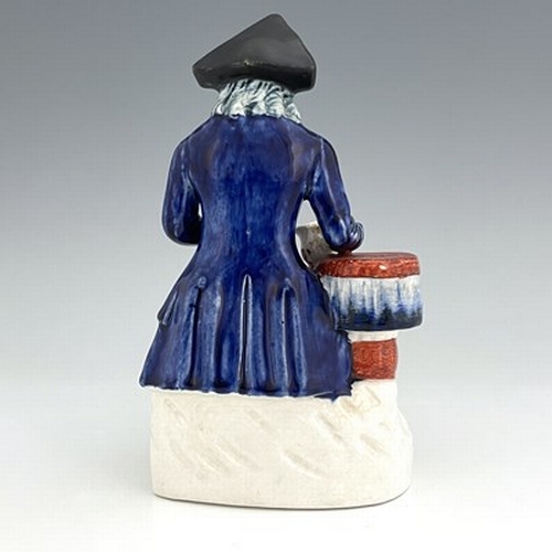 1060 - A Staffordshire figure of a Greenwich Hospital pensioner, circa 1850, modelled as a seated sailor wi... 