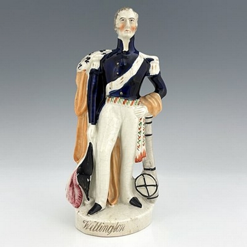 1075 - A Staffordshire portrait figure of Wellington, circa 1840, modelled standing in his blue dress unifo... 