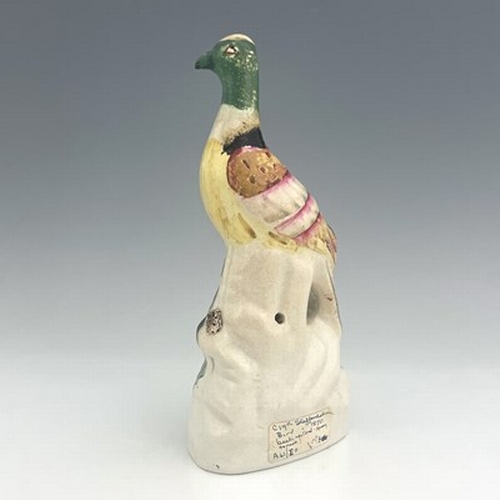 1089 - A Staffordshire pottery exotic bird, circa 1850, modelled perched on a green and brown mound, on an ... 