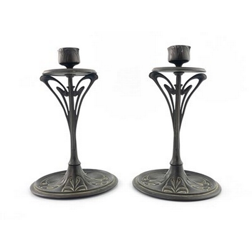 135 - A pair of bronze Art Nouveau candlesticks, disc drip-pan on sinuous openwork stem to circular dished... 