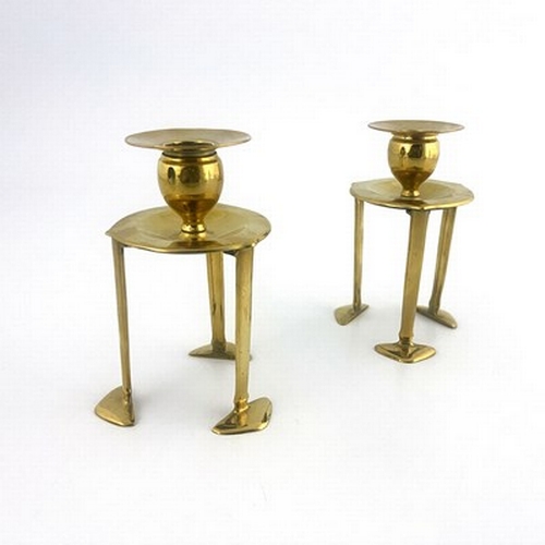 150 - A pair of Arts and Crafts brass candlesticks, in the style of C F A Voysey, 1906, each with three ve... 