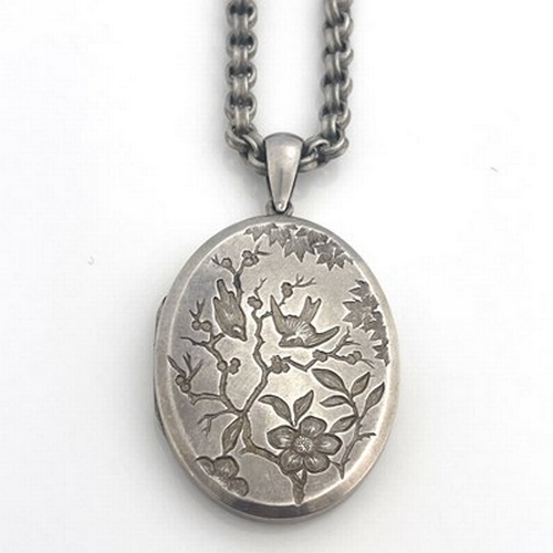 28 - A Victorian Aesthetic Movement white metal locket on chain, incuse embossed with ferns and birds to ... 