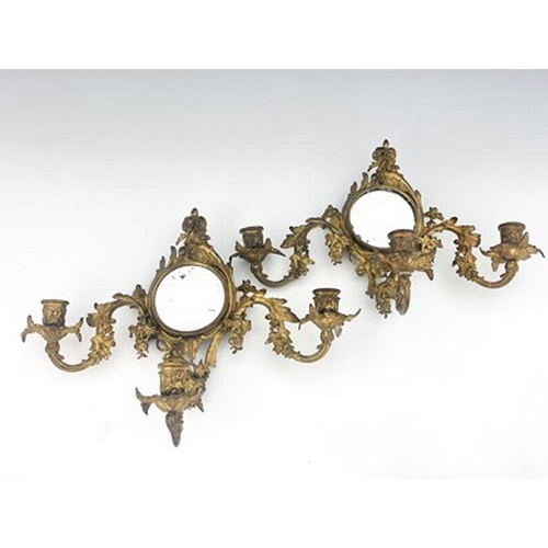 289 - A pair of gilt metal girandoles, late 19th Century, of Rococo design, circular looking glasses, trip... 