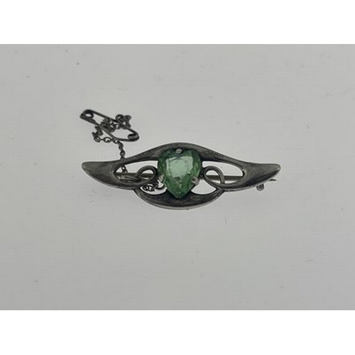 29 - An Arts and Crafts silver and green stone set brooch, the central heart shaped gem within a winged k... 