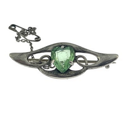 29 - An Arts and Crafts silver and green stone set brooch, the central heart shaped gem within a winged k... 