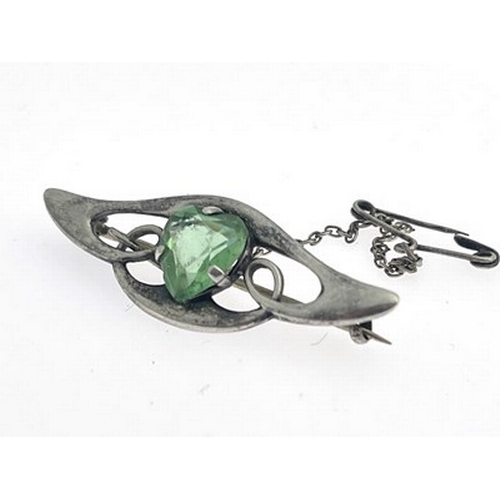 29 - An Arts and Crafts silver and green stone set brooch, the central heart shaped gem within a winged k... 