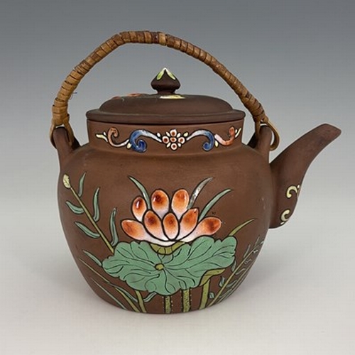 564 - A Chinese Yixing teapot and cover, enamelled with water plants and flowers, swing top handle, 19cm w... 