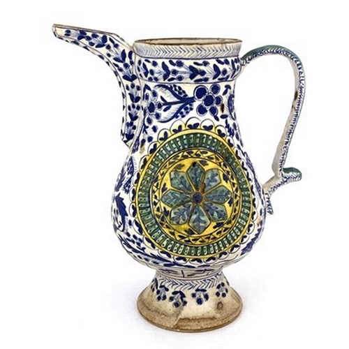 569 - A Turkish Ottoman pottery ewer, footed baluster form, relief moulded floral roundels within blue and... 