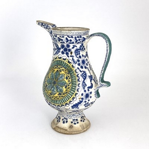 569 - A Turkish Ottoman pottery ewer, footed baluster form, relief moulded floral roundels within blue and... 