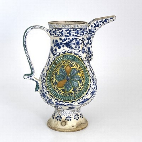 569 - A Turkish Ottoman pottery ewer, footed baluster form, relief moulded floral roundels within blue and... 