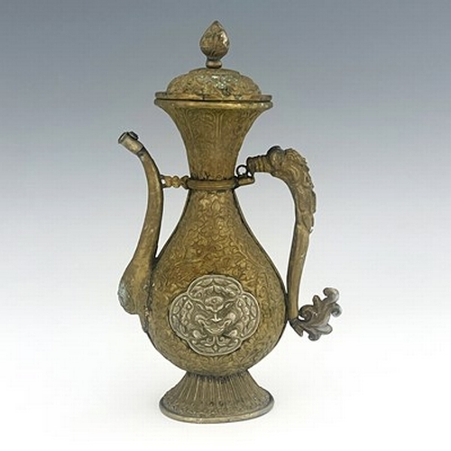 586 - A Persian white metal and brass ewer, embossed and chased in relief with foliate scroll design