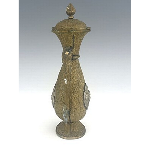 586 - A Persian white metal and brass ewer, embossed and chased in relief with foliate scroll design