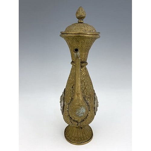 586 - A Persian white metal and brass ewer, embossed and chased in relief with foliate scroll design