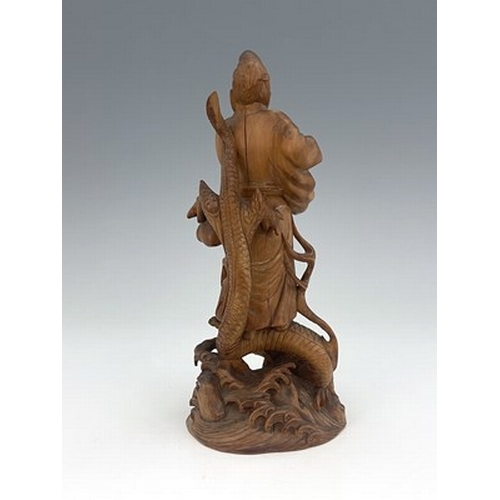 588 - A Chinese carved figure of a scholar, modelled holding a scroll, standing on a writhing dragon, 21cm... 