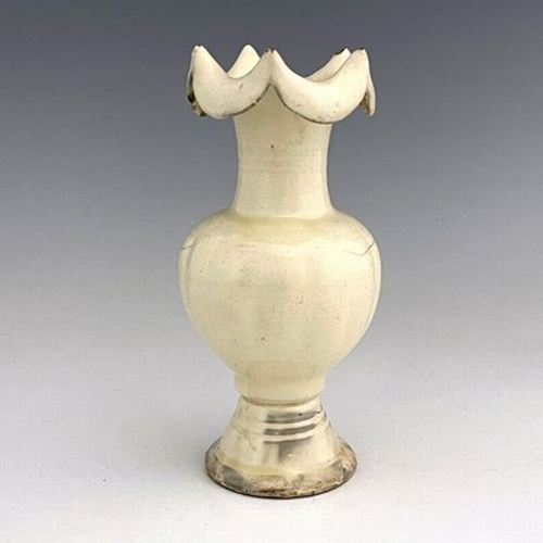 616 - A Chinese cream glazed earthenware vase, probably Tang, the melon form ovoid body with wave crimped ... 