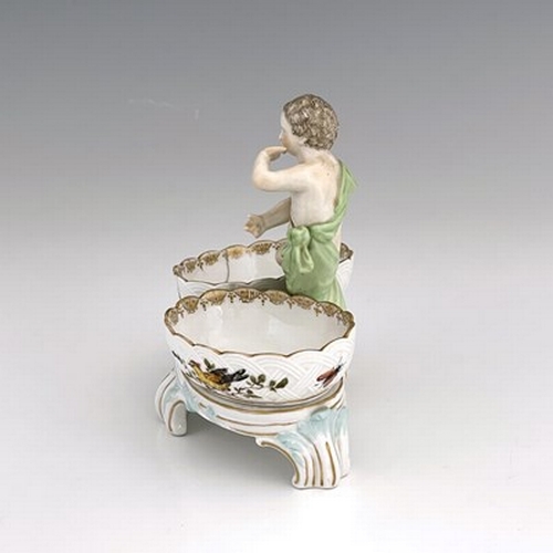 794 - A Berlin porcelain figural double salt cellar, 19th century, the central putto between two basket mo... 