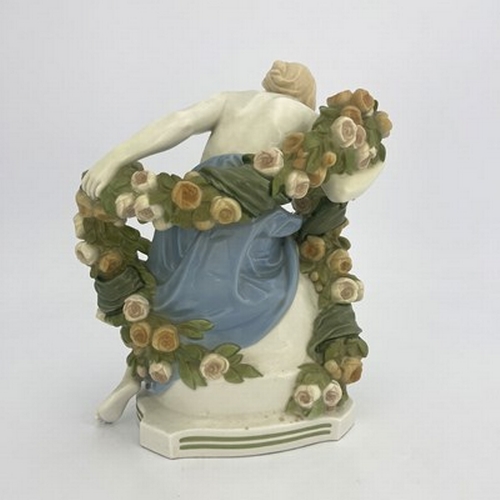 827 - Paul Schley for KPM, an Art Deco female nude figure, modelled seated with a garland of roses, impres... 