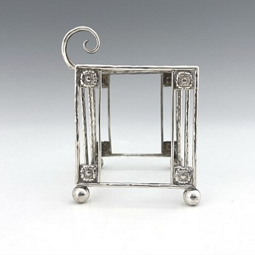 93 - A E Jones, an Arts and Crafts silver three division toast rack, Birmingham 1918, planished wire cons... 