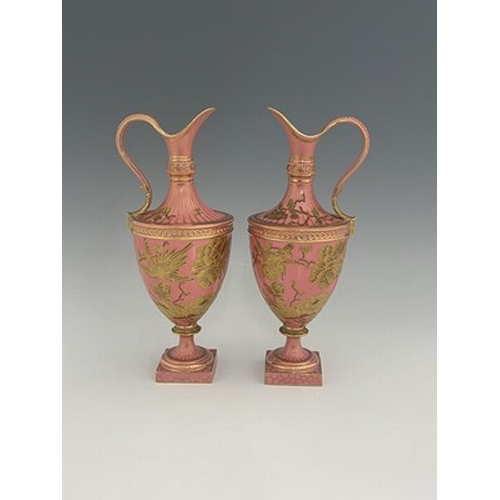 931 - A pair of Royal Crown Derby pink ground and gilt Derby Ewers, 1886, painted in the Aesthetic style w... 