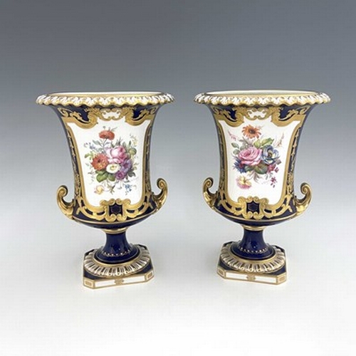 941 - Albert Gregory for Roal Crown Derby, a pair of twin handled Campana Urn vases, 1920, painted with fl... 