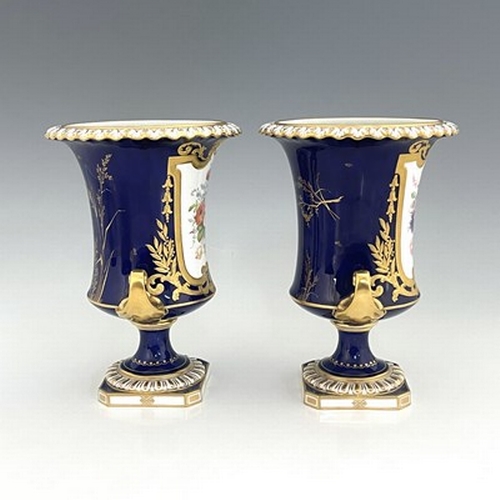 941 - Albert Gregory for Roal Crown Derby, a pair of twin handled Campana Urn vases, 1920, painted with fl... 