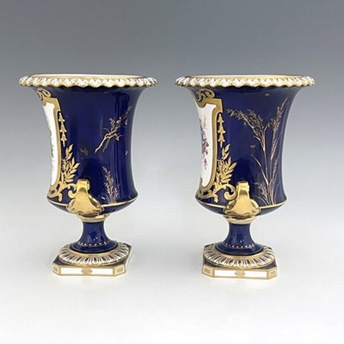 941 - Albert Gregory for Roal Crown Derby, a pair of twin handled Campana Urn vases, 1920, painted with fl... 