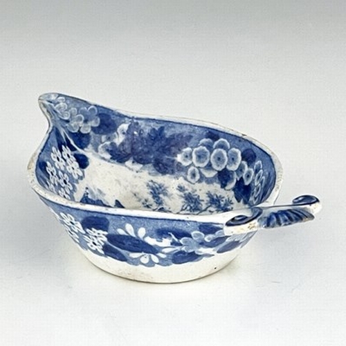 959 - A pearlware blue and white pap boat, circa 1800, relief moulded shell handle, decorated with gardene... 