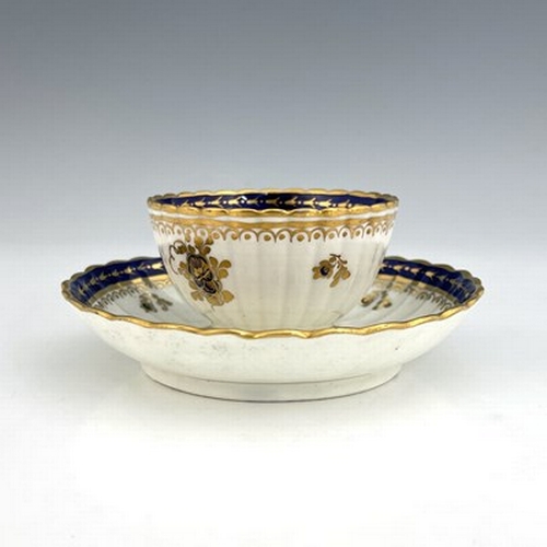 975 - A Caughley tea bowl and saucer, blue S mark, circa 1780, reeded and fluted, with blue and gilt flora... 