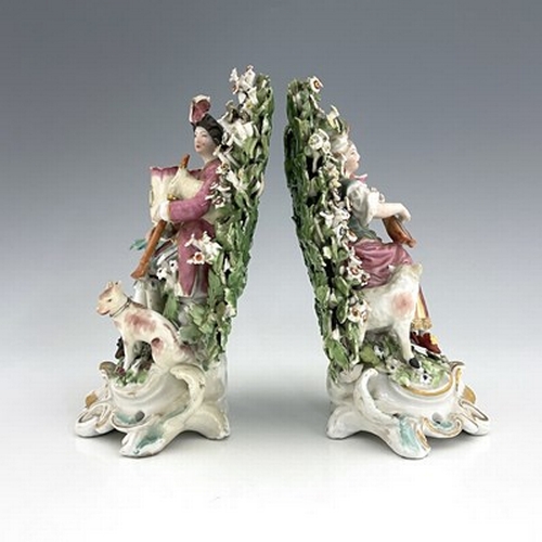 997 - A pair of Derby porcelain shepherd and shepherdess figural candlesticks, circa 1770, bocage backed, ... 