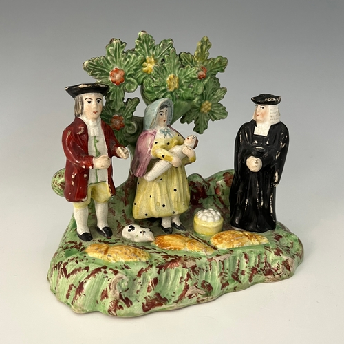 1046 - A Staffordshire 'Tythe Pig' figure group, circa 1820, modelled with three figures beneath flowering ... 