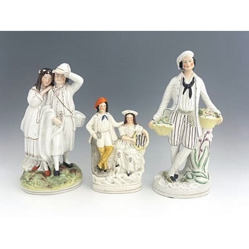 128 - Three Staffordshire figure groups , circa 1865, one modelled as a standing male fruit seller in whit... 