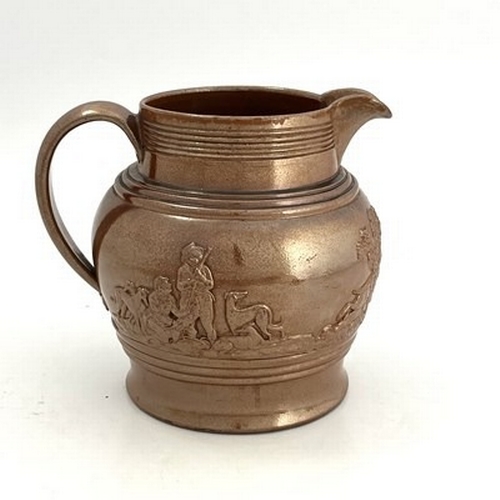 207 - A large brown glazed jug, circa 1820, relief moulded with rural hunting scene. 23 cm tall.