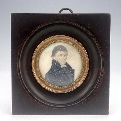 297 - An early 19th century portrait miniature painted to depict a man in a high-collared blue coat, on iv... 