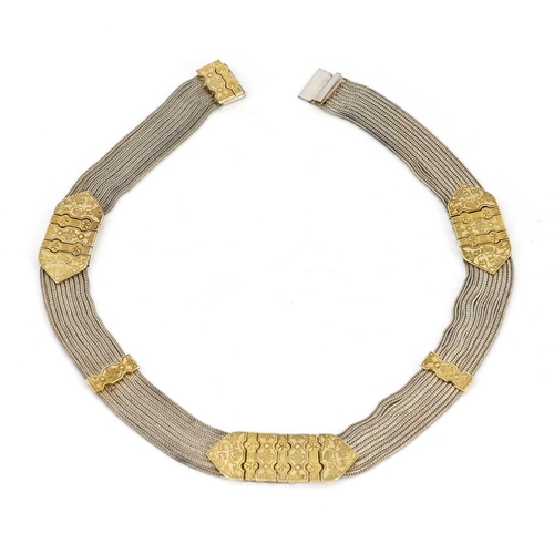24 - A Middle Eastern silver and parcel gilt choker necklace, nine chain mesh strands united by tooled gi... 