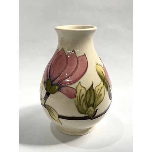 176 - A Walter Moorcroft for Moorcroft, Magnolia patterned baluster shaped vase, set on a consistent cream... 