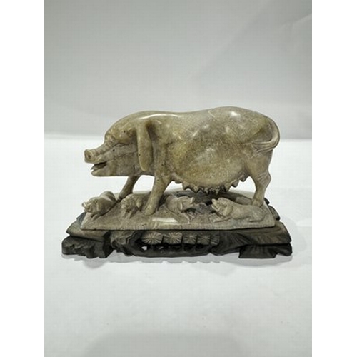 512 - A Chinese hand-carved soapstone figure group of a sow suckling piglets, mounted on a wooden stand, 1... 