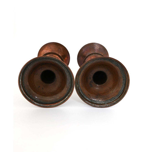 181 - Richard Llewellyn Rathbone, a pair of Arts and Crafts copper candlesticks, saucer knopped conical fo... 