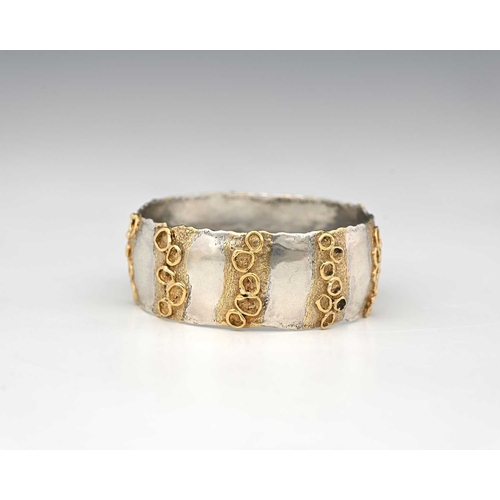 45 - Jane Watling, a Modernist parcel gilt silver bangle, London 1990, irregular edged band form with str... 