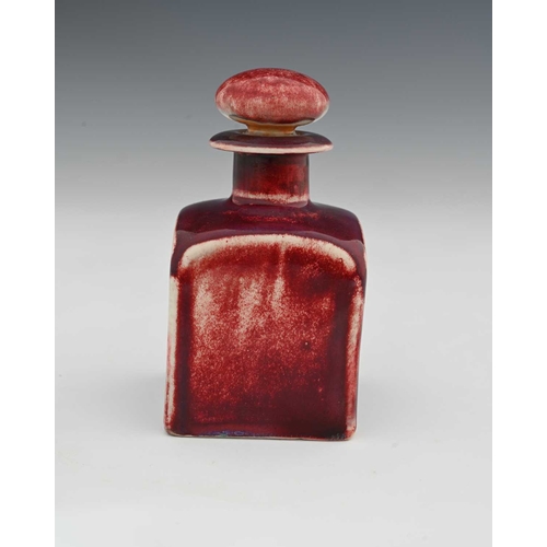 629 - Ruskin Pottery, a High Fired scent bottle, circa 1920s, cuboid form with bun stopper, red sang de bo... 