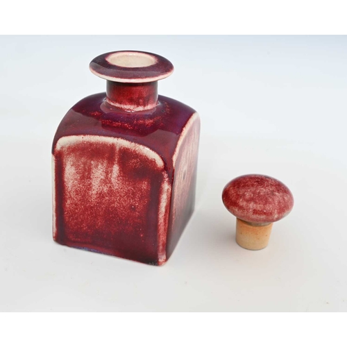 629 - Ruskin Pottery, a High Fired scent bottle, circa 1920s, cuboid form with bun stopper, red sang de bo... 