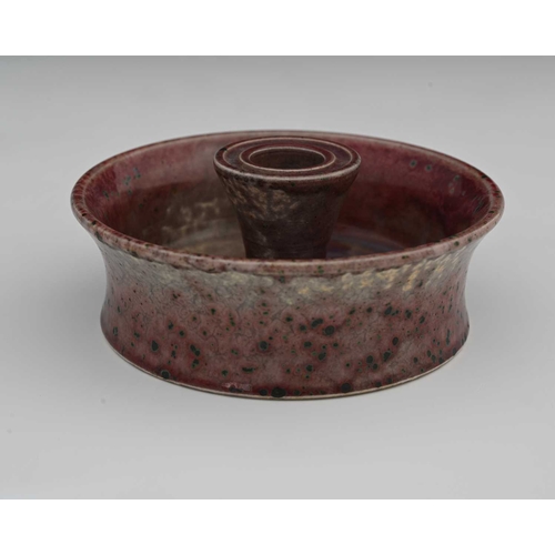 636 - Ruskin Pottery, a High Fired candle holder, 1931, flared circular dish form with central conical sco... 